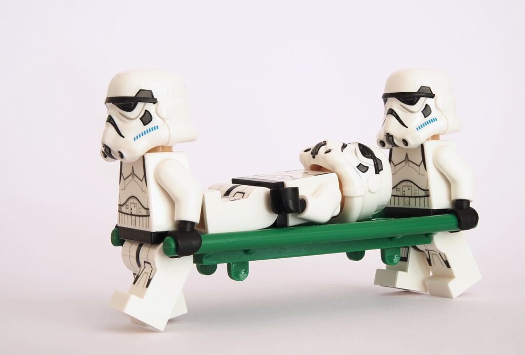 story; storm trooper Legos carrying one storm trooper on a stretcher